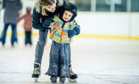 mother helping young son ice skate